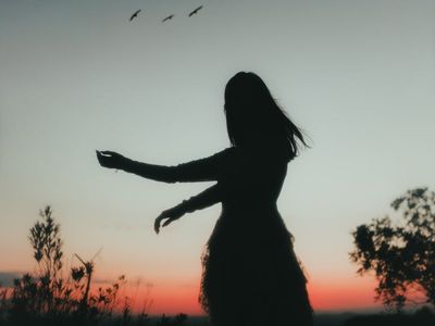 Silhouetted figure moving through a graceful stretching sequence.